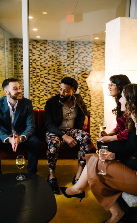 people sitting around a table chatting with drinks in hand