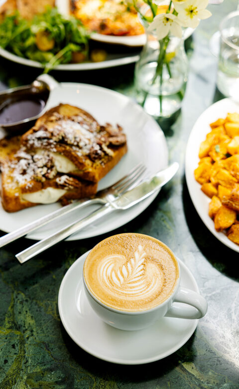 a table topped with plates of food and a cup of coffee