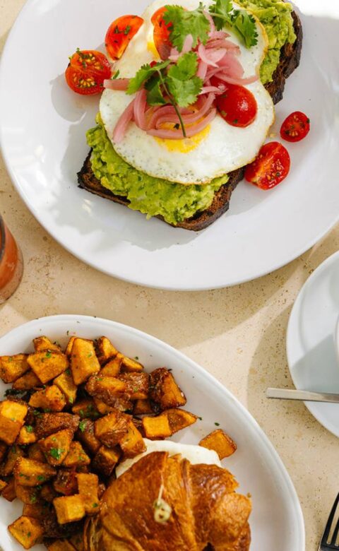 a table topped with plates of food and a cup of coffee