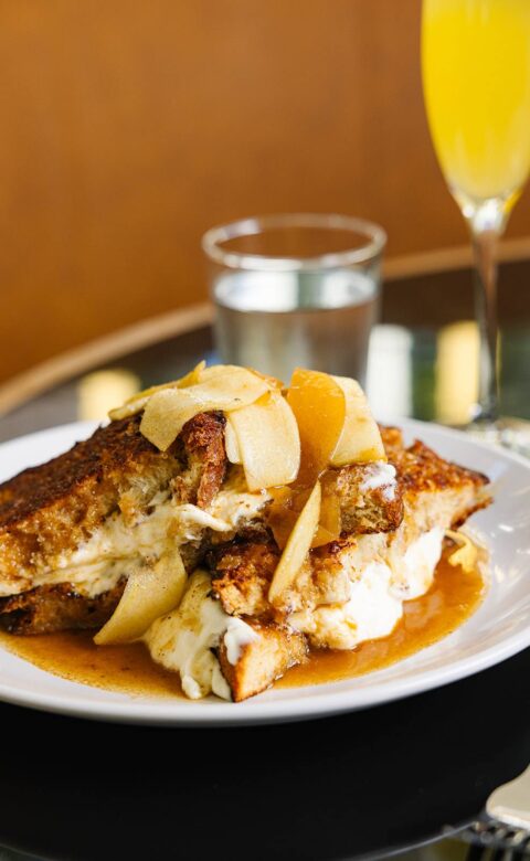 a plate of food on a table with a glass of orange juice